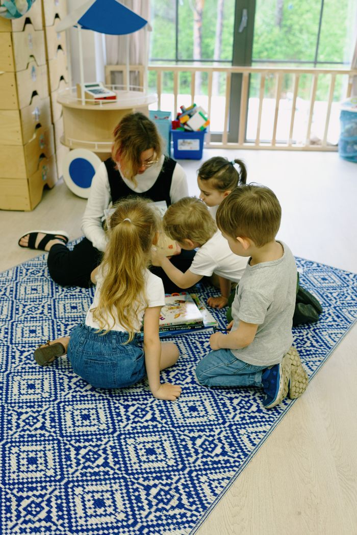 Young children and teacher in a kindergarten reading session indoors.